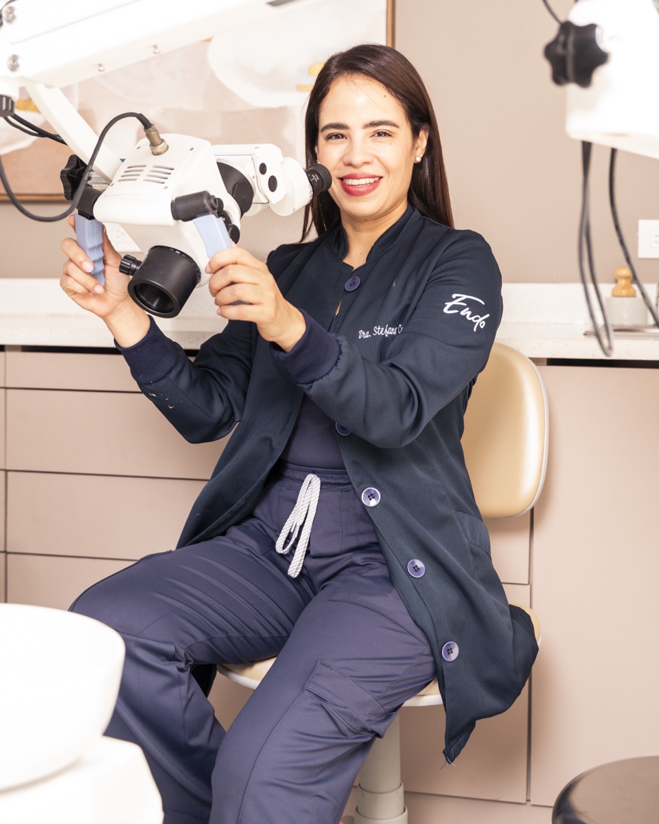 Dr. Stefany Colato with operating microscope at Clínica Endodontics — the equipment that changes diagnosis from extraction to saving the tooth